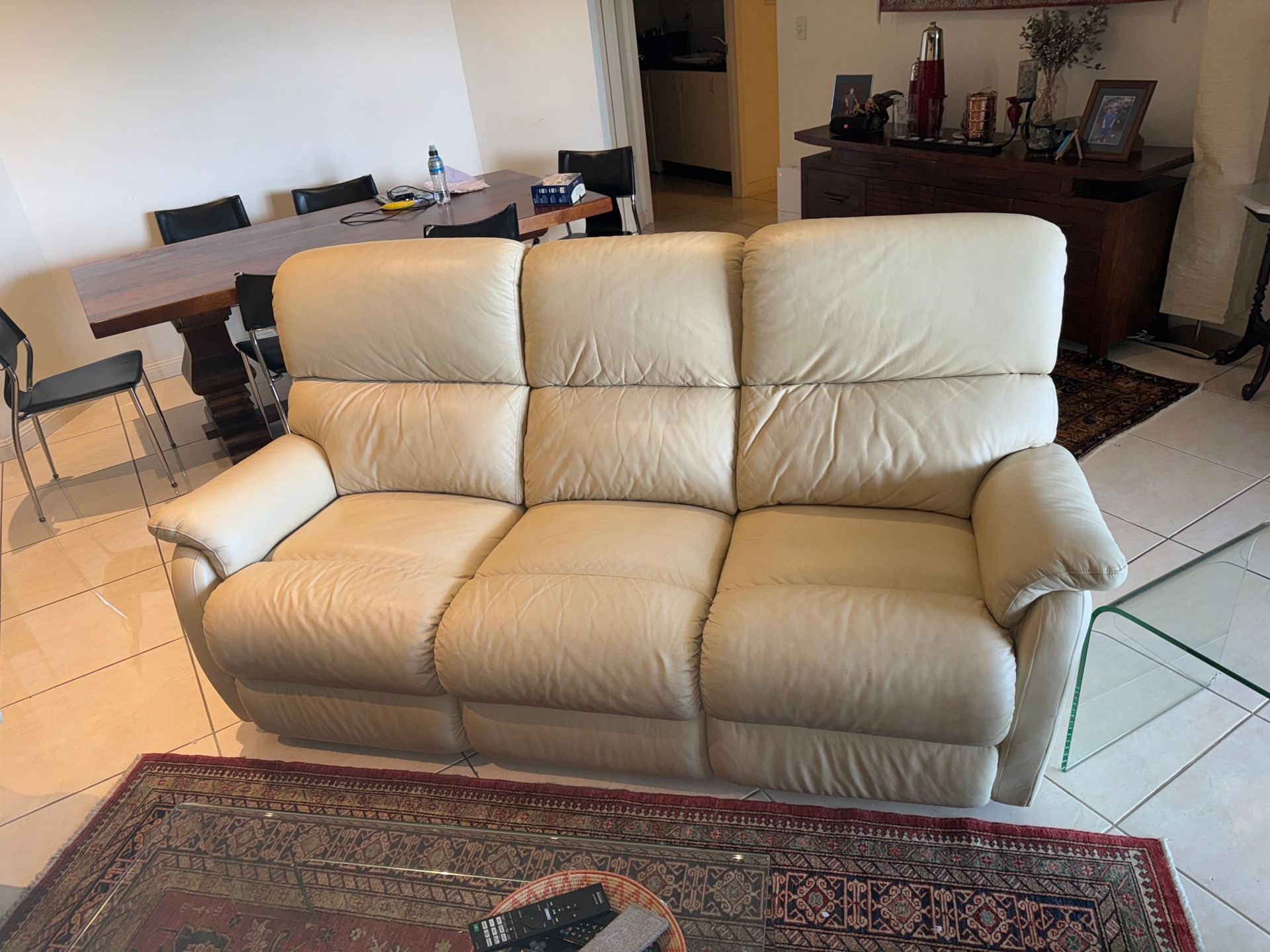 A white leather couch is sitting in a living room next to a rug.