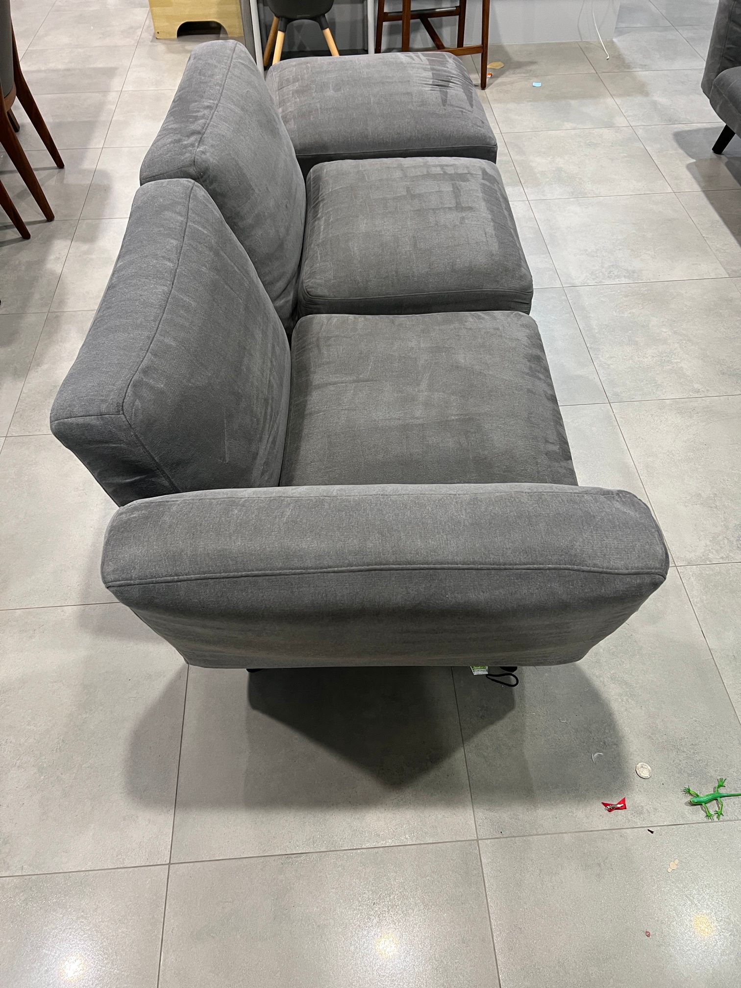A grey couch is sitting on a tiled floor in a living room.