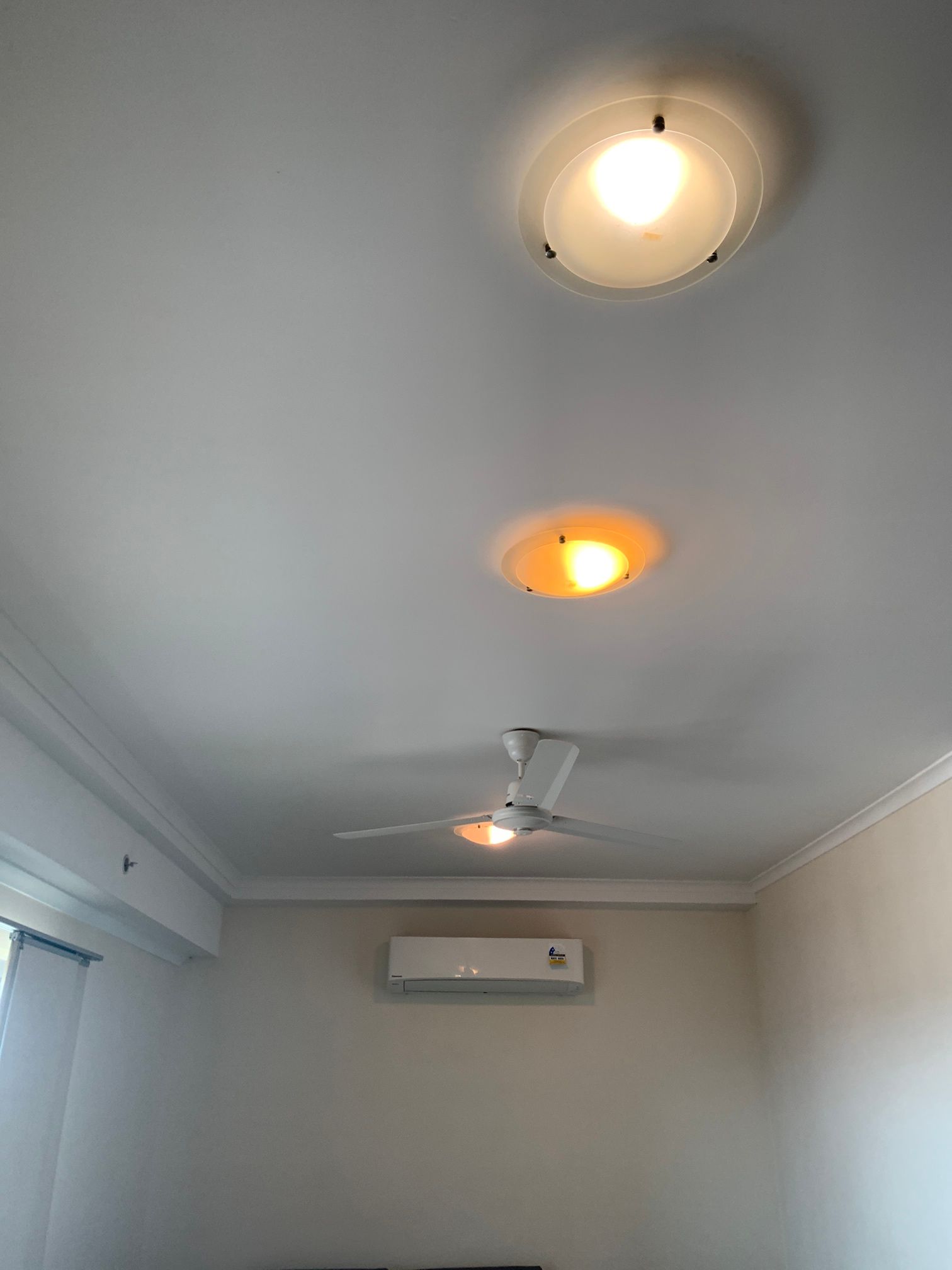 A room with a ceiling fan and three lights on the ceiling.