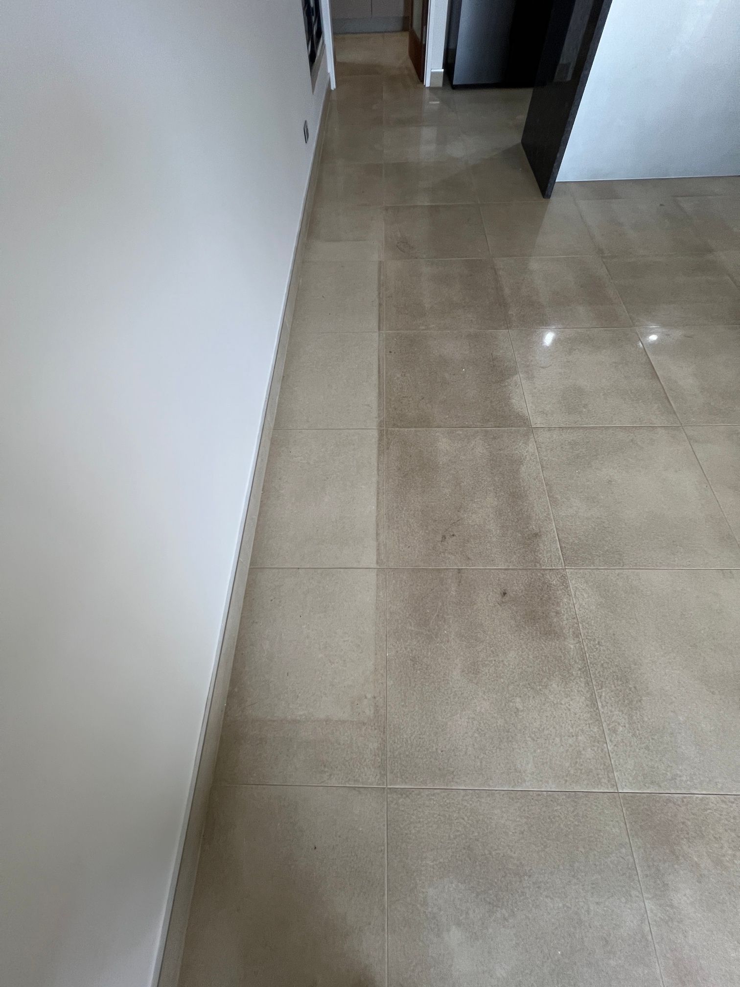 A hallway with a tiled floor and a white wall.