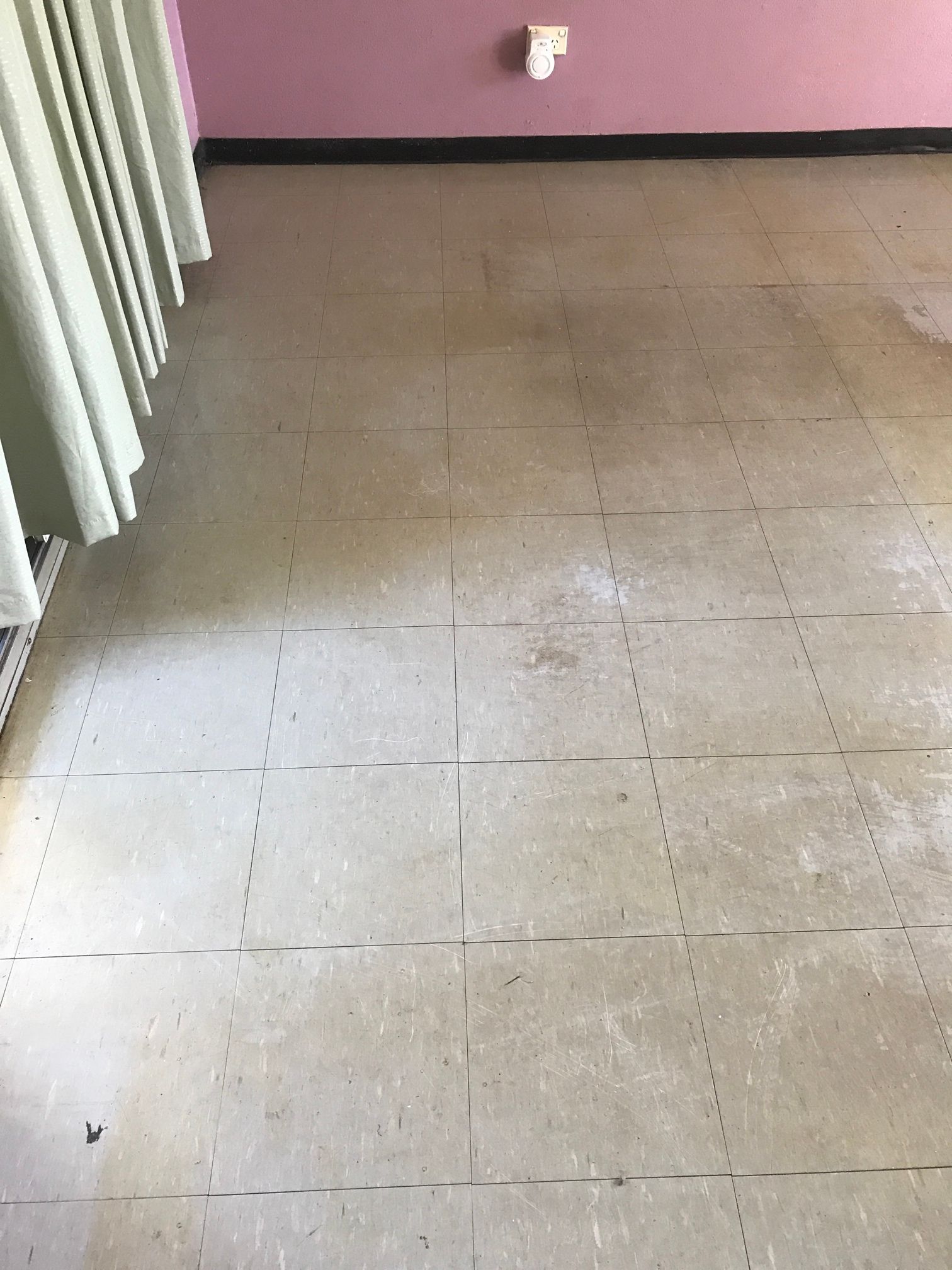 A room with a tiled floor and a pink wall.