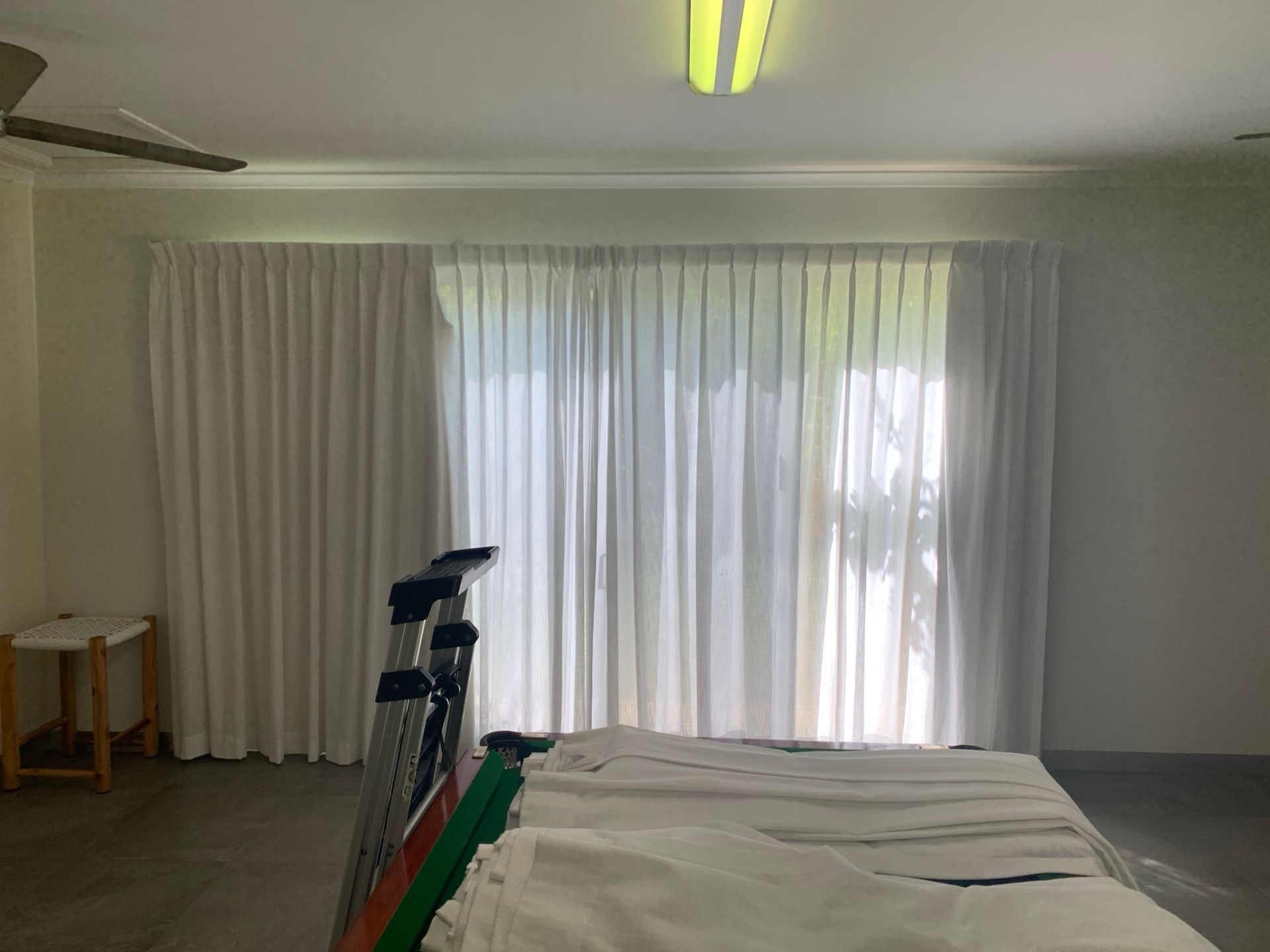A bedroom with white curtains and a sliding glass door.